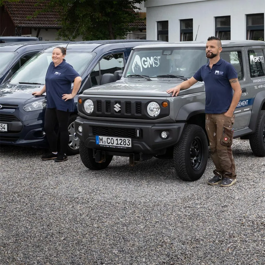 Zwei GM-Süd-Mitarbeiter vor ihrem Einsatzfahrzeug